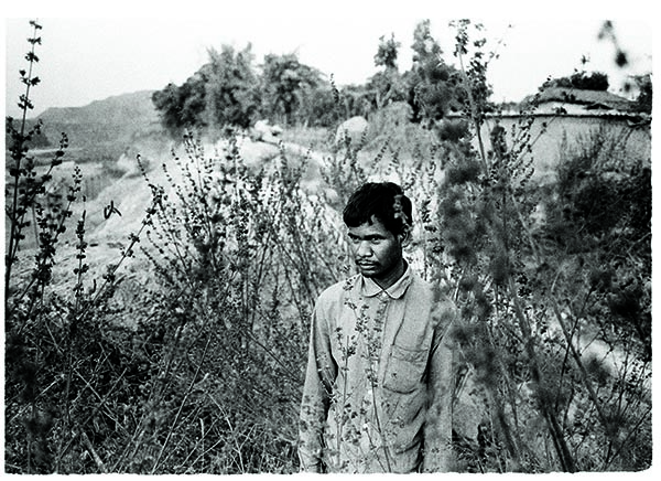 A villager from Sarasmal village, Chhattisgarh, in 2014, looks out toward what used to be his land before he was pressured into selling 12 acres. He now has land enough for his house, which sits right on the boundary of a large steel mine. Daily blasting sessions in the mine rattle and shake his house, scaring his infant son. “I’m hoping they will employ me in the mine at least,” he says.